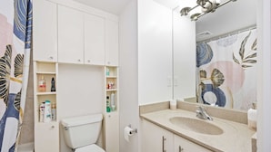 A bathroom with a toilet, a sink, and a mirror. - Stylish Waterfront Studio Near Parks & City Core (Toronto)