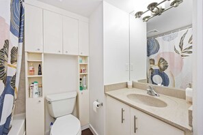 A bathroom with a toilet, a sink, and a mirror. - Stylish Waterfront Studio Near Parks & City Core (Toronto)