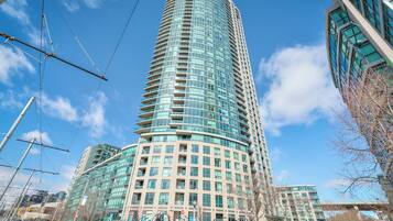 A tall, modern building with a curved facade, surrounded by a clear sky and other buildings.