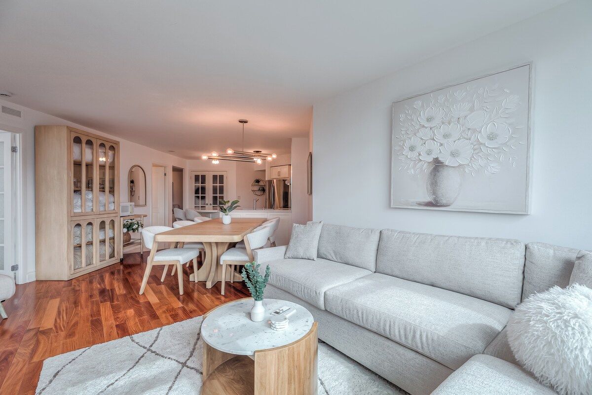 Uma sala de estar moderna com sofá, mesa de jantar e mesa de centro.