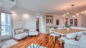Un salón espacioso con una mesa de comedor de madera, sofás blancos y un ventanal grande.