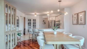 A modern kitchen with a wooden dining table, white chairs, and a built-in oven.