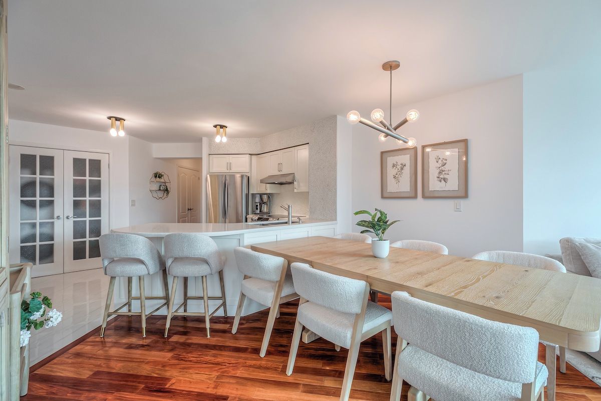 Una cocina moderna con armarios blancos, una mesa de comedor de madera y taburetes de bar.