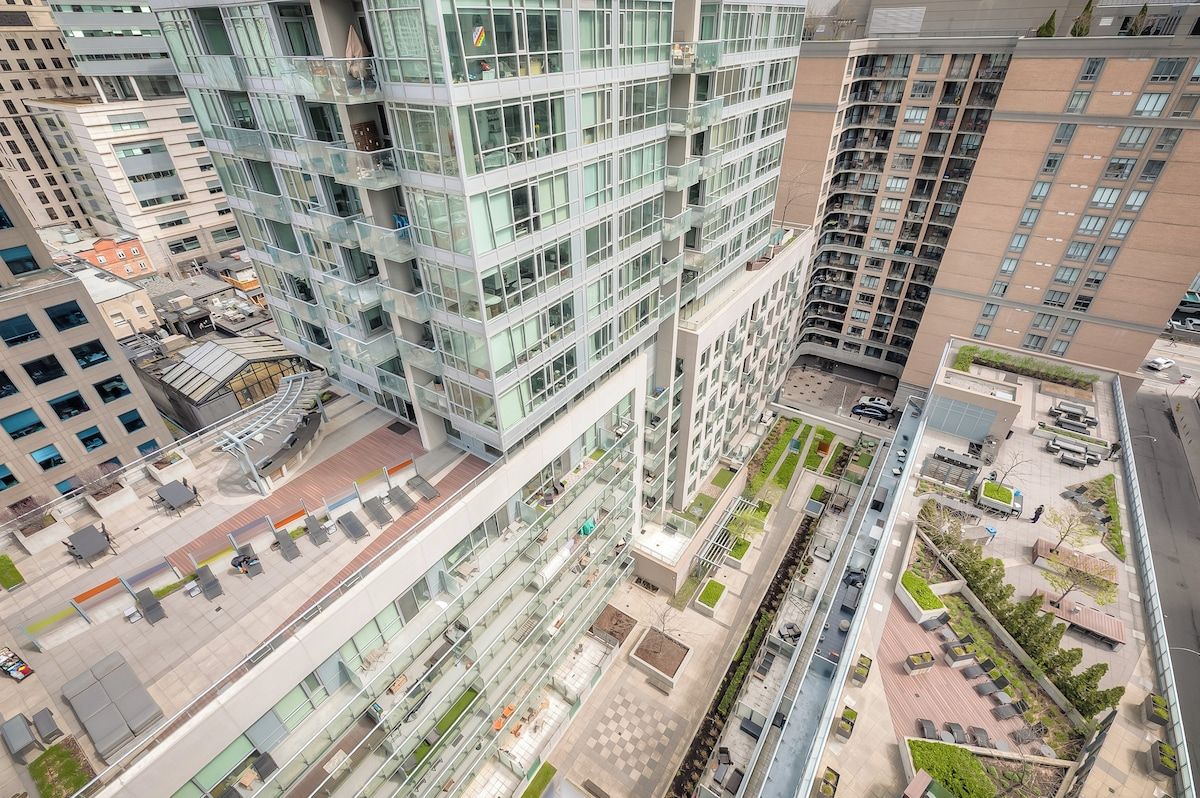 A high-rise building with multiple floors, large windows, and a rooftop terrace with outdoor seating.