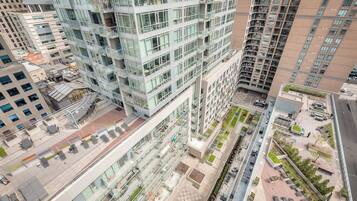 A high-rise building with multiple floors, large windows, and a rooftop terrace with outdoor seating.