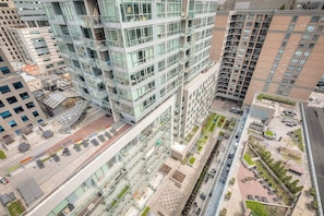 A high-rise building with multiple floors, large windows, and a rooftop terrace with outdoor seating. - CN Tower Views - 2BR Condo - Balcony - Fast Wi-Fi (Toronto)