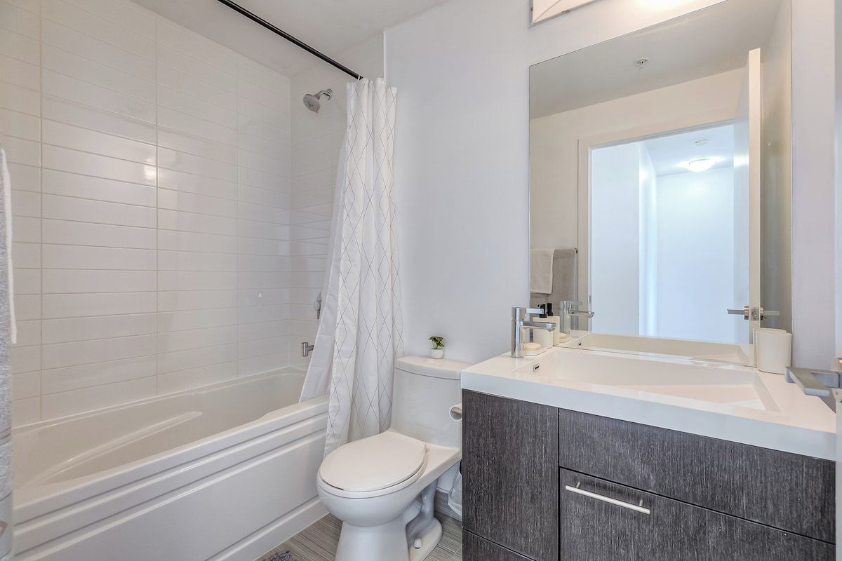 A modern bathroom with a bathtub, toilet, and vanity with a mirror.