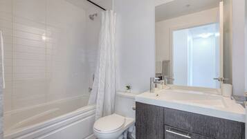 A modern bathroom with a bathtub, toilet, and vanity with a mirror.