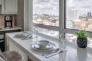 Una cocina moderna con comedor, cafetera y vistas a la ciudad.