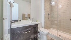 Une salle de bain moderne avec une douche à parois de verre, des toilettes blanches et un meuble-lavabo avec un miroir.
