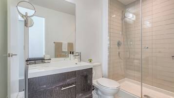 A modern bathroom with a glass-enclosed shower, a white toilet, and a vanity with a mirror.
