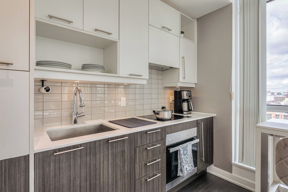 A modern kitchen with white cabinets, a stainless steel sink, and a built-in oven.