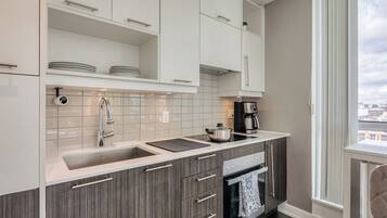 A modern kitchen with white cabinets, a stainless steel sink, and a built-in oven.