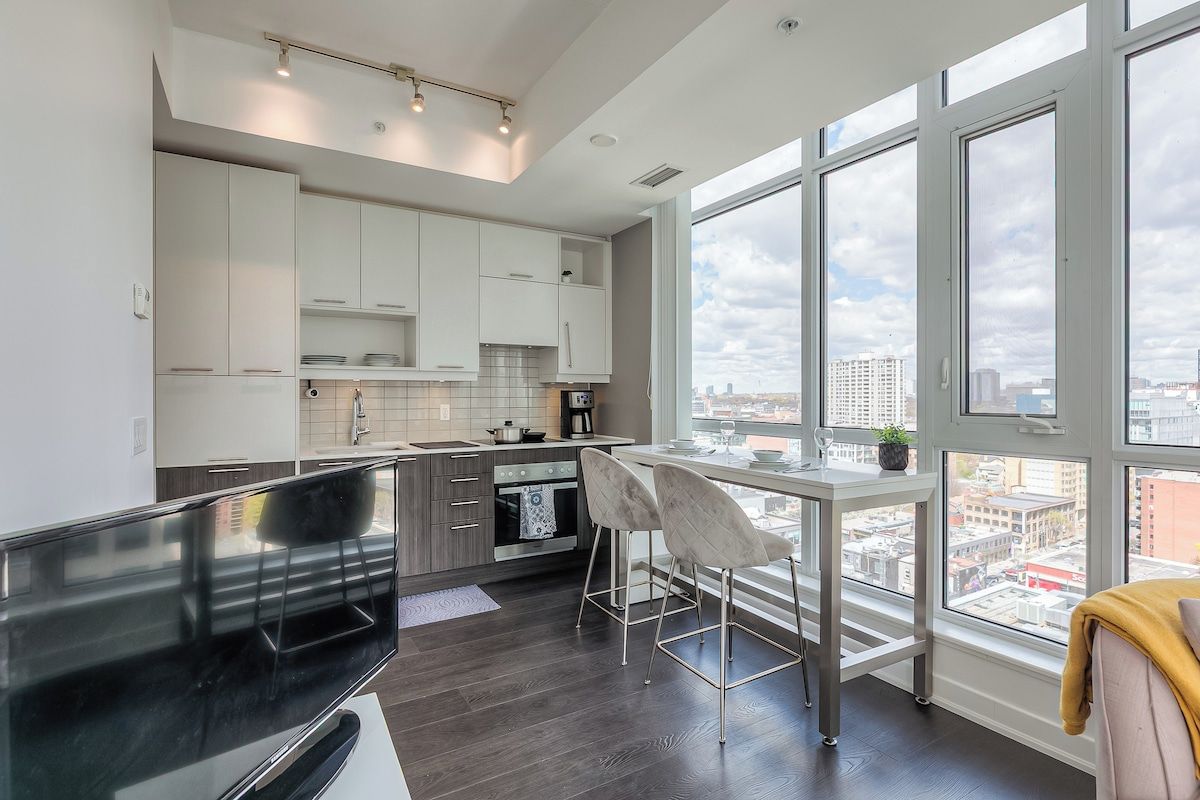 Una cucina moderna con mobili bianchi, un'ampia finestra e vista sulla città.