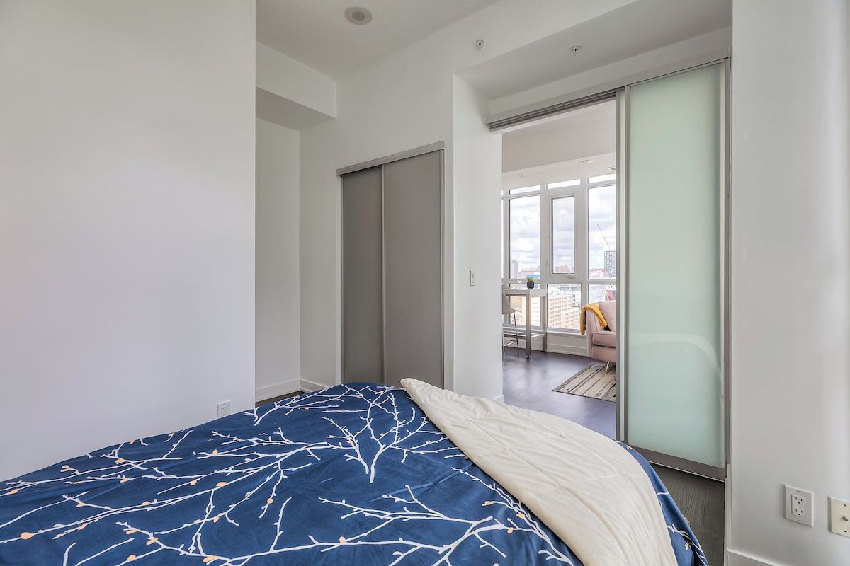 A bedroom with a bed, a sliding door, and a view of a balcony with a chair.