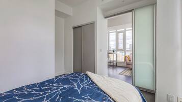 A bedroom with a bed, a sliding door, and a view of a balcony with a chair.