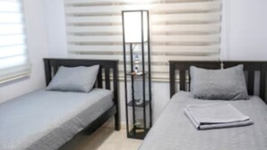 Ein Schlafzimmer mit zwei Betten, einem Kleiderschrank und einem Fenster mit Jalousien.