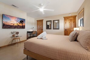 Ein Schlafzimmer mit Bett, Schreibtisch, Stuhl, Deckenventilator und einem Bild an der Wand.