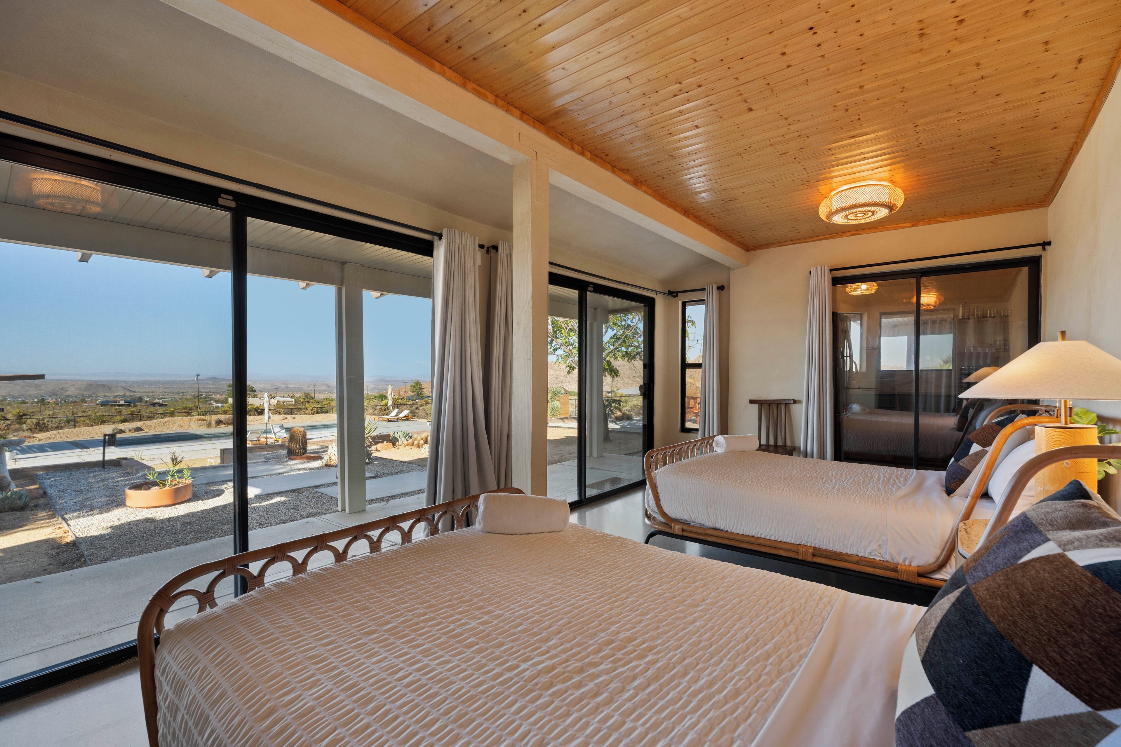 A bedroom with two beds, a large window, and a view of the landscape.