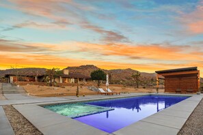 Ein Pool mit klarem, blauen Rand, umgeben von einer angelegten Grünfläche mit Stufen, die zu einem Haus führen.