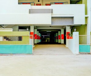 A building entrance with a concrete pathway leading to a set of doors. - Classic With Balcony Rama Home Stay (Tirupati)
