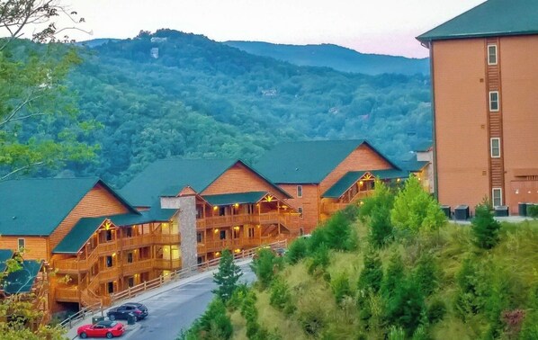 Eine Lodge mit mehreren Holzhäusern, einer Straße davor und einer bergigen Kulisse.