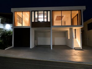 Un edificio moderno de dos pisos con grandes ventanales y una escalera que conduce al nivel superior.