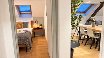 Une petite pièce comprenant un lit, une table de chevet et une lucarne au plafond.