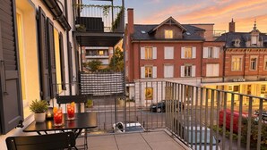A balcony with a table, chairs, and a potted plant. - book2stay: Apartment with Balcony near harbor & train station (Romanshorn)