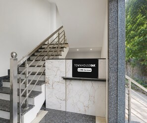 A staircase with a metal railing and a sign indicating 'TOWNHOUSE OAK' with 'OYO-Serviced' below it. - Deluxe Govindpuri Station Formerly Montto Plaza (Kanpur)