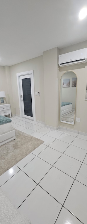 Quarto com cama, mesa de cabeceira, espelho e ar condicionado.