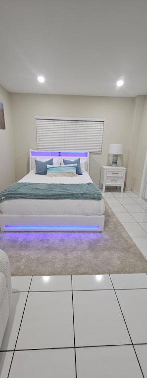 A bedroom with a bed, bedside tables, a lamp, and a window with blinds. - Gorgeous 1-bedroom house with AC in vibrant Miami,..free parking (Miami)