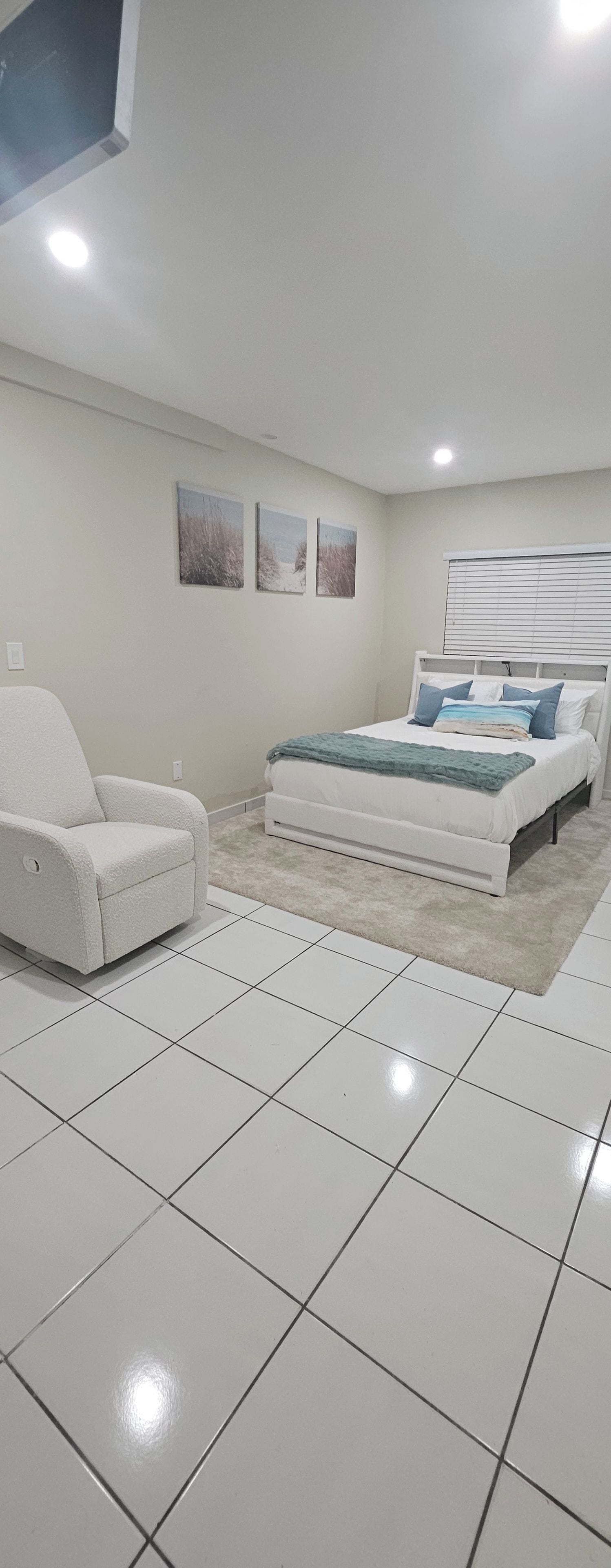 A bedroom with a bed, a chair, and a window.