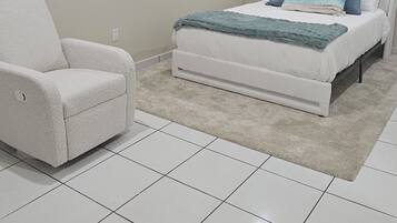 A bedroom with a bed, a chair, and a window.