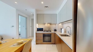 Eine moderne Küche mit Essbereich, ausgestattet mit Backofen, Mikrowelle und Spüle aus Edelstahl.
