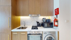 Een moderne keuken met een spoelbak, fornuis, magnetron en wasmachine.