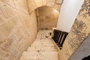 A narrow stone staircase with a metal handrail, leading to an arched doorway. - Historic Valletta House, 3BR & Terrace (Valletta)