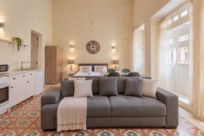 A spacious room with a sofa, a bed, a dining table, and a kitchen area. - Historic Valletta House, 3BR & Terrace (Valletta)