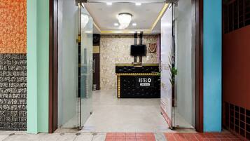 A hotel reception area with a black reception desk, a clock, and a chandelier.