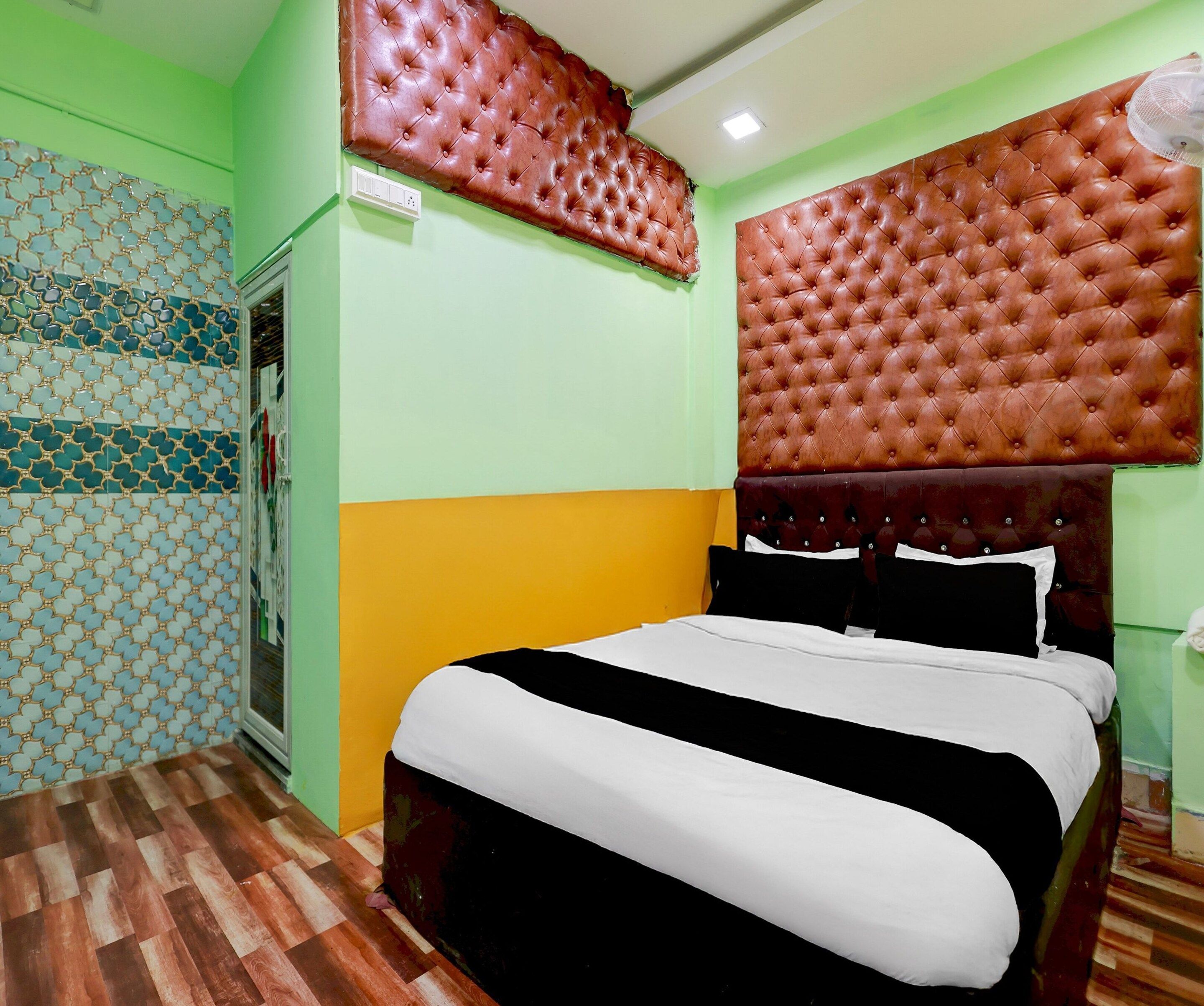 A room with a bed, a wall with a geometric pattern, and a ceiling fan.