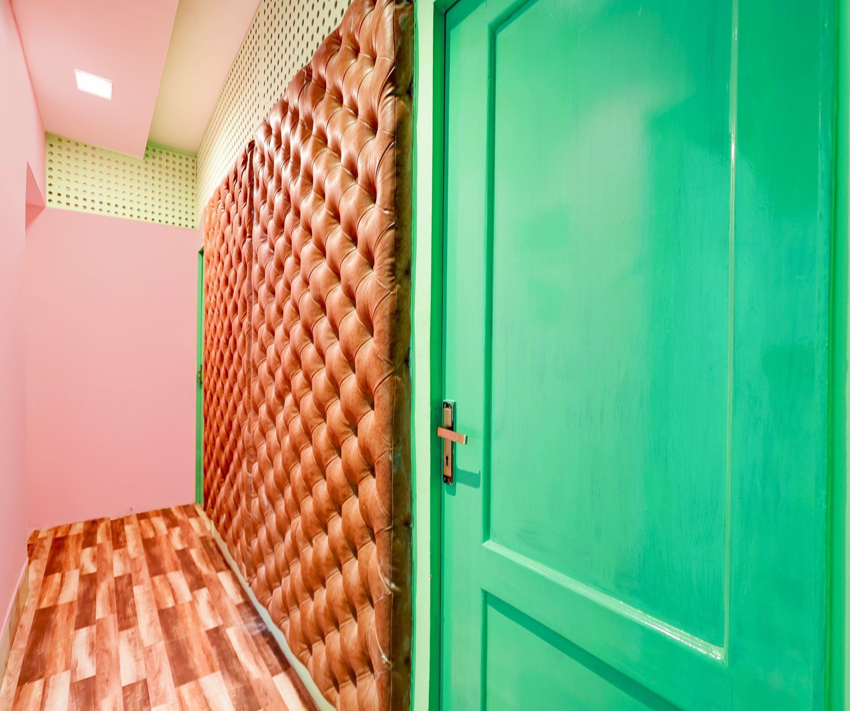 A room with a green door, a patterned wall, and a wooden floor.