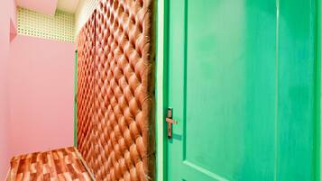 A room with a green door, a patterned wall, and a wooden floor.