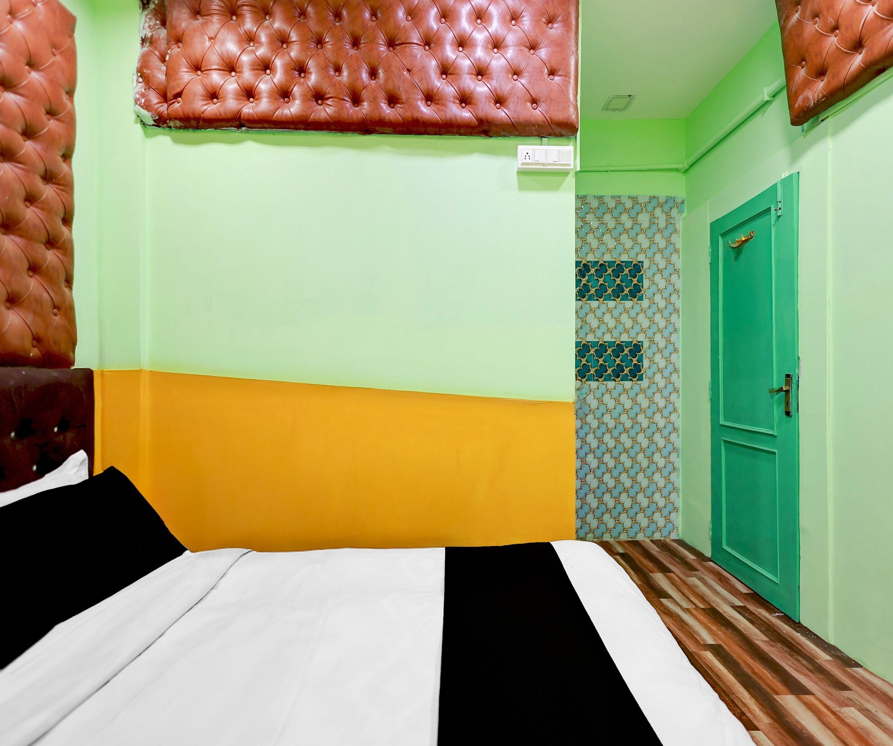 A room with a bed, a green door, and a patterned wall.