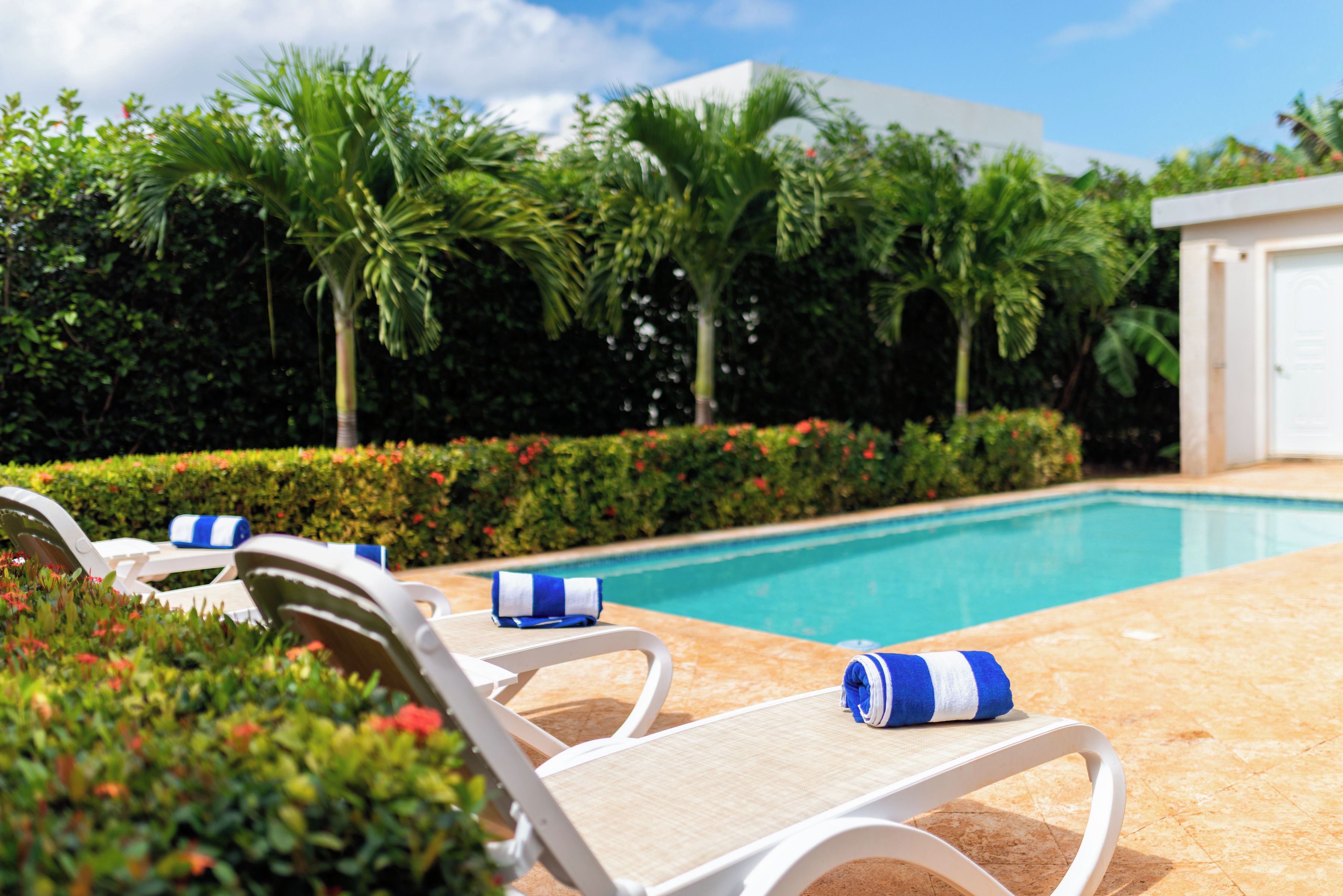 Un área junto a la piscina con sillas de descanso y una piscina.