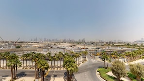 A construction site with palm trees and a road. - Serene Meydan Studio | Distant Burj Khalifa View (Meydan)
