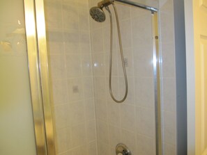Una dutxa amb plat de robaç i aixeta de pared.