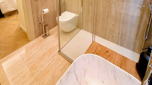 Ein modernes Badezimmer mit einer gläsernen Duschkabine, einer Marmorbadewanne und einer Toilette.