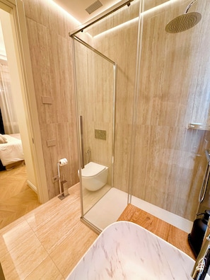 Un baño moderno con ducha de vidrio, bañera de mármol y retrete.