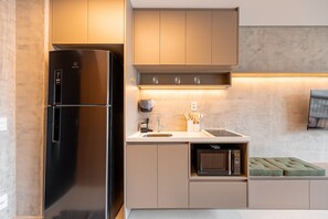 A modern kitchen with a stainless steel refrigerator, a microwave, and a built-in oven. - Yuny - Zip  Morumbi (São Paulo)