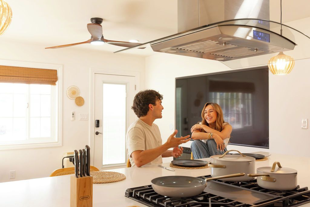A modern kitchen with a central island, a stove, and overhead ventilation.